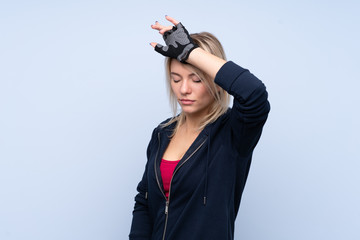 Young sport blonde woman over isolated blue background with tired expression