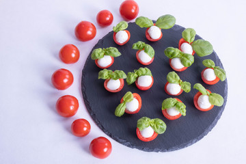 composition of basil, tomatoes and mozzarella on a stone black tile