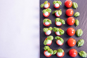 composition of vegetables, tomatoes, mozzarella on a stone black tile
