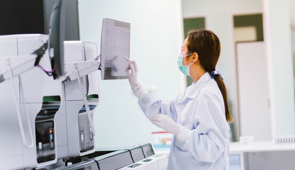 young female laboratory technician working with automation blood  analyzer in medical laboratory