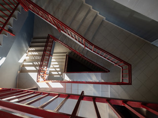Perspective view of a beige staircase in the staircase with red railing leading to the bottom.