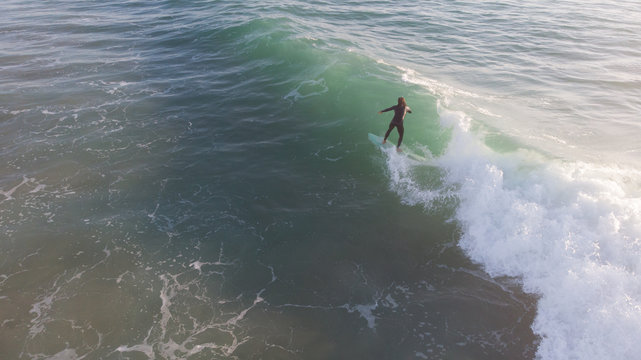 Surfero cabalgando una ola con perspectiva a&eacute;rea 