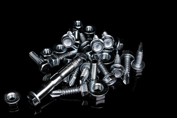 Mix of fasteners.  Bolts, nuts, screws, anchor bolts on a black background.  Assorted Fixing...