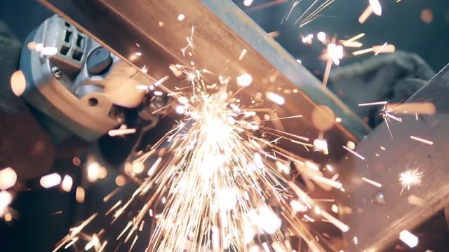 A man cuts metal with a grinding machine.