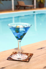 A glass of drink beside the pool