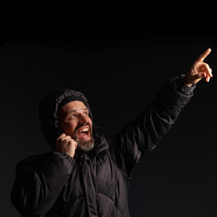 Portrait of a man in a hooded jacket. Studio shooting, dark background.