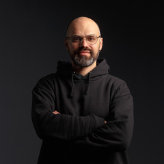 Portrait of a man in a hooded jacket. Studio shooting, dark background.