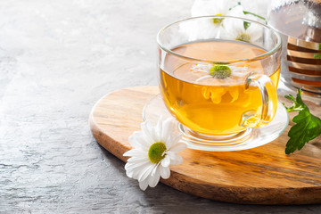 Herbal tea with camomile on a light background. Cup of tea with herbs and dried fruits on a gray concrete table. Vitamin drink.