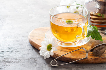 Herbal tea with camomile on a light background. Cup of tea with herbs and dried fruits on a gray concrete table. Vitamin drink.