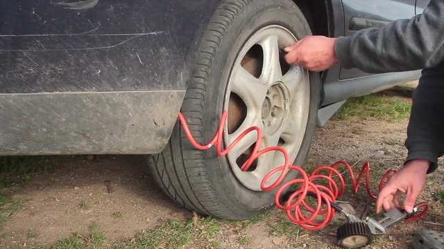 close up of repair of a flat tire with tire inflation with a compressed air compressor where the tire visibly swells
