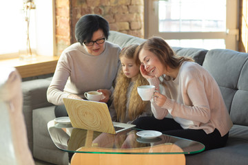 Comfortable. Happy loving family. Grandmother, mother and daughter spending time together. Watching cinema, using laptop, laughting. Mother's day, celebration, weekend, holiday and childhood concept.