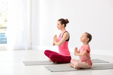 Fototapeta na wymiar Young mother with little daughter practicing yoga at home