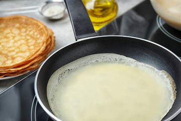 Delicious thin pancake in frying pan on induction stove, closeup