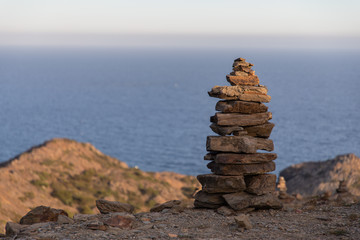 Fototapeta na wymiar View of a structure of stacked stones in front of a sea view with copy space