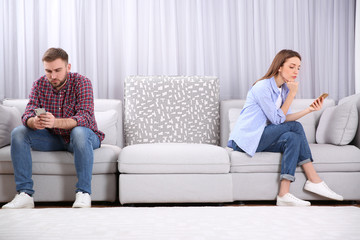 Obraz premium Couple addicted to smartphones ignoring each other at home. Relationship problems