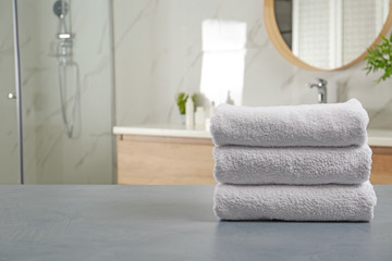 Stack of clean towels on grey stone table in bathroom. Space for text