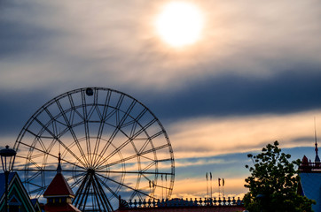 Silhouette of ferris wheel with alone cabin on the blue and orange cloudy sky backgorund against the sunset. Mood concept.
