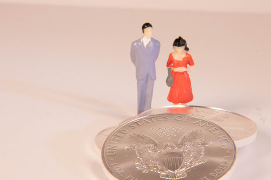 Male and female miniature figures standing behind US silver eagle coins