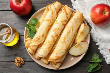 Delicious thin pancakes on wooden table, flat lay