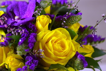 Close-up of a beautiful spring bouquet with yellow roses and purple orchids. Decorative composition of a greeting card for a birthday holiday. Copy space.