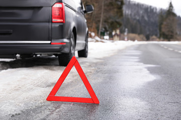 Emergency stop sign and broken car on winter day