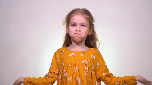A little girl puffs out her cheeks and slaps them with her hands