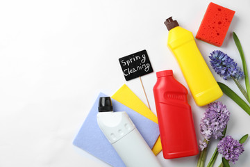 Composition with Spring Cleaning sign, flowers and detergents on white background, top view