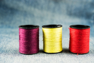 Three reels of thread and jeans. Sewing as hobby.