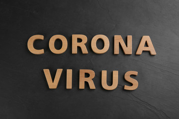 Words CORONA VIRUS made of wooden letters on black table, top view