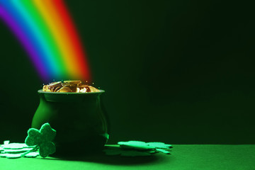 Pot with gold coins and clover leaves on green table, space for text. St. Patrick's Day celebration