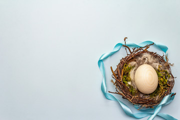 Easter bird nest. Zero waste, DIY concept. Soft feathers, egg, moss. Light blue background