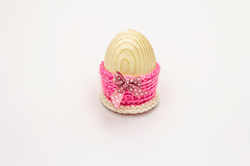 Wooden egg in pink crocheted stand isolated on white background. Easter zero waste concept