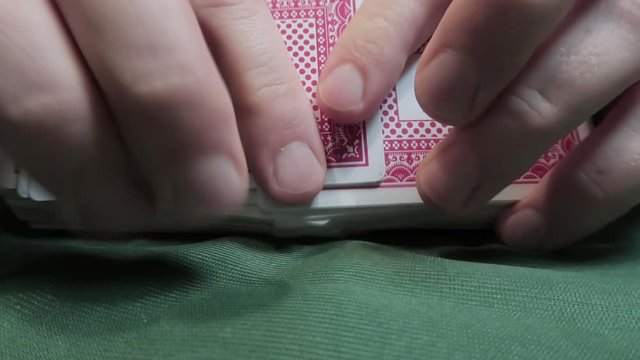 Riffle Shuffle. Male hand shuffling cards on green cloth. Close-up. Gambling. Games of chance