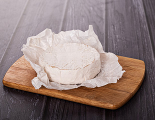 brie cheese in white paper on a wooden table