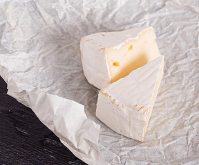 brie cheese in white paper on a wooden table