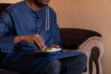 man eating ugali by hand while holding the plate