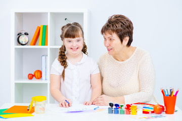 Fototapeta premium Girl with Down Syndrome works with her teacher at home