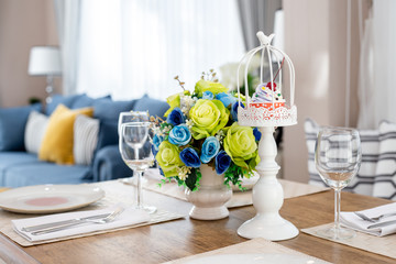 Blue and green roses in white vases and cupcakes on the table