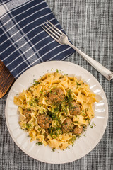 Tagliatelle pasta with pork meatballs and dill sauce. Selective focus.