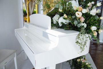 white piano with black keys whose circle are beautiful flowers