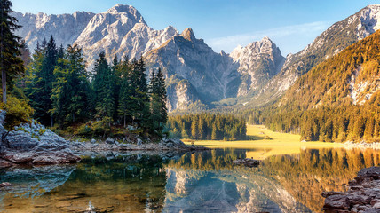 Wonderful Autumn landscape during sunset. Great view on fairy tale Fusine lake under sunlight. ...