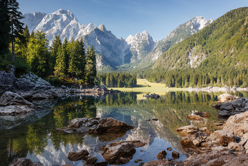 Obraz na płótnie Canvas Scenic image of fairy-tale Mountain lake under sunlit. Amazing Nature Landscape. Wonderful sunny morning. Beautiful scenery of the majestic Fusine lakeside in Julian Alps. Perfect natural background