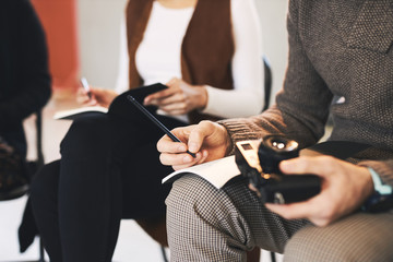 Closeup of man on photogrphy class holding camera and taking notes.