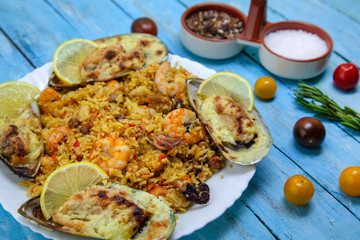 spanish seafood paella, close up view in plate on wooden blue table