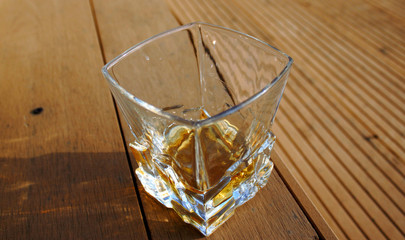 glass glass with whiskey, outside on a wooden textured surface, on a Sunny day