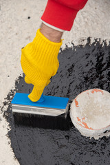 Worker applies bitumen mastic on the foundation