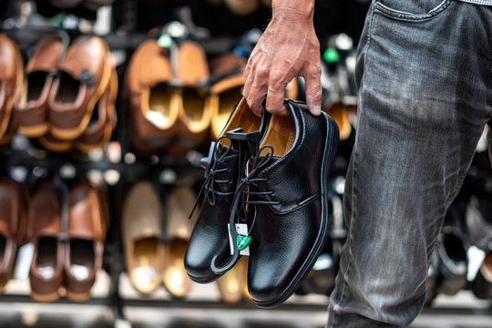 image of Man holding the shoes in hand, shopping in the male store.