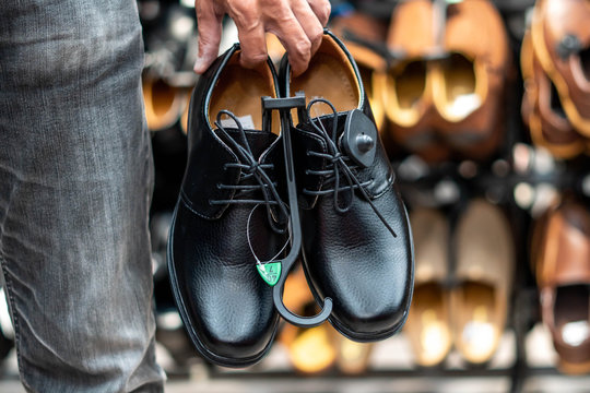 image of Man carrying beautiful couple choosing classic shoes while doing shopping in the male store.
