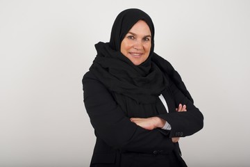 Pretty caucasian lady standing against gray wall with arms crossed wearing casual clothes. Looking and smiling at the camera. Confident successful woman.