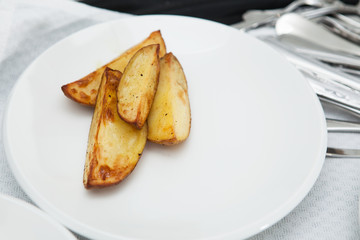 Fragrant wedges of french fries on a white plate.  Closeup.
